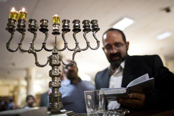 Iranian Jewish Rabbi Younes Hamami Lalehzar reads prayers after lighting candles to mark Hanukkah, the festival of lights, at Abrishami synagogue in downtown Tehran on November 28, 2013.