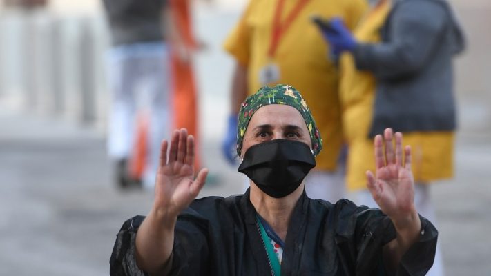 A healthcare worker acknowledges applause outside the Gregorio Maranon Hospital in Madrid on April 12, 2020 during a national lockdown to prevent the spread of the COVID-19 disease [Pierre-Philippe Marcou/AFP]